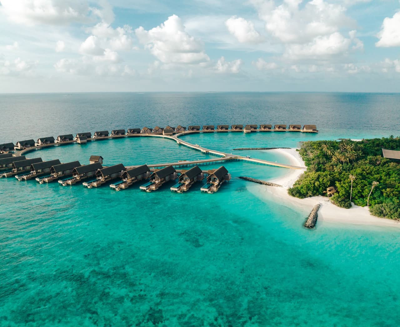 Island shoreline and overwater villas, aerial view at Joali Being