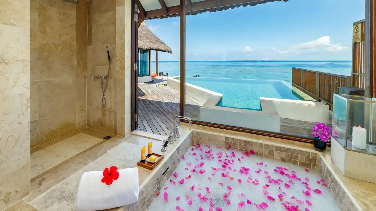 Spa bathtub with flower petals and lagoon view at Ozen Reserve Bolifushi