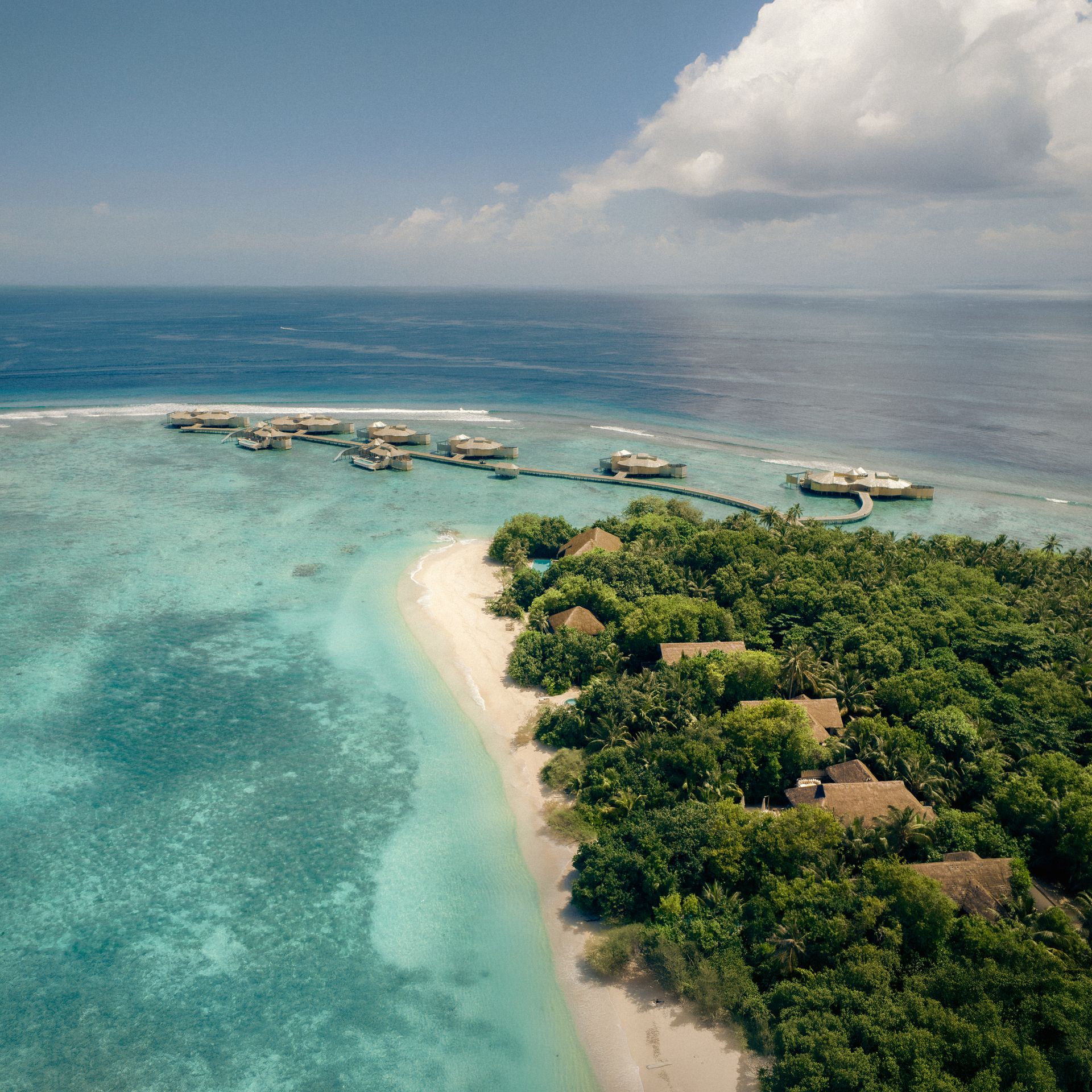 Island shoreline and water-villa jetty, aerial view at Soneva Fushi