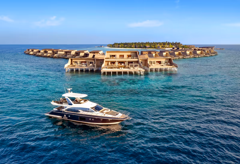 Yacht in front of overwater villas at The St. Regis Maldives Vommuli Resort