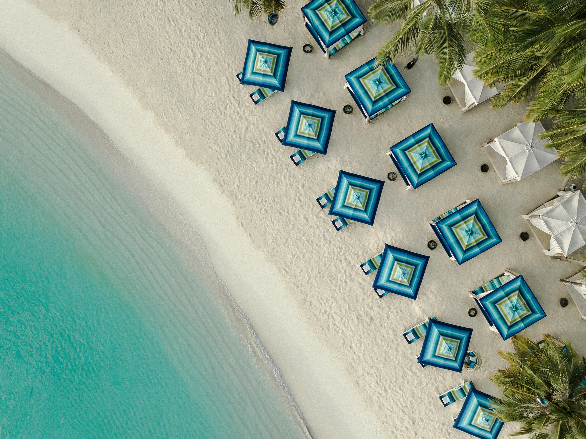 Aerial view of turquoise water and striped beach umbrellas at One&Only Reethi Rah
